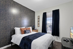 A bedroom with a bed, a nightstand, a TV, and a window with curtains. - Windsor Palms 3 Bed Condo In Gated Resort 3 Bedroom Condo (Kissimmee)