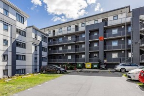 A multi-story residential building with balconies, a parking area, and a clear sky. - Eden Vista Apartment 3 Bedrooms with free parking (Auckland)