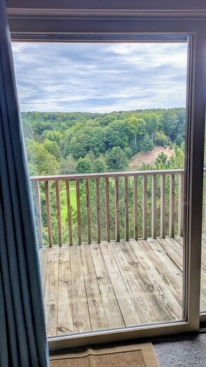 A wooden deck with a view of a forested landscape. - Welcome to Bellaire Base Camp at Shanty Creek Resorts, in Beautiful Bellaire, MI (Bellaire)