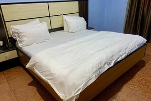 Una habitación de hotel con una cama, una mesita de noche y un cabecero fijado a la pared.