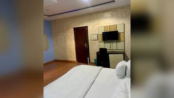 Una habitación de hotel con cama, televisor, escritorio y puerta.