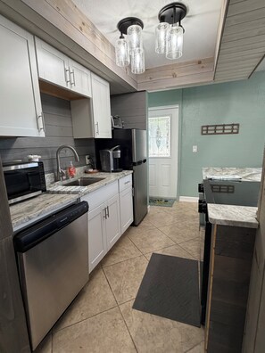 Een moderne keuken met roestvrijstalen apparatuur, witte kasten en een zwart aanrecht.
