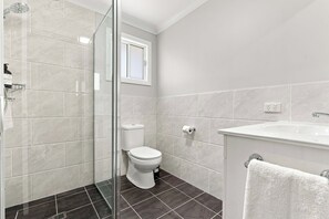 Ein Badezimmer mit Duschkabine, Toilette und Waschbecken mit Handtuch.