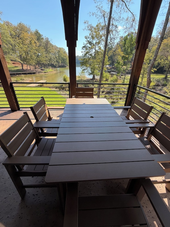 An outdoor seating area with a table and benches, overlooking a lake and trees.