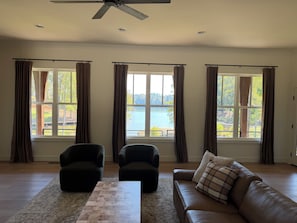 A spacious living room with a large window overlooking a lake, two armchairs, a sofa, and a ceiling fan. - Relaxing & Spacious Lake Life at NEW 'The Cove' (Alexander City)