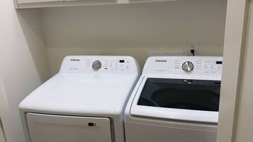 Uma lavanderia com duas máquinas de lavar brancas de carregamento frontal e armários acima.