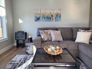 A living room with a grey sofa, a coffee table with decorative items, and abstract wall art.