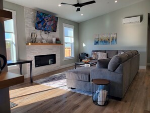A modern living room with a fireplace, a gray sofa, a coffee table, and artwork on the walls.