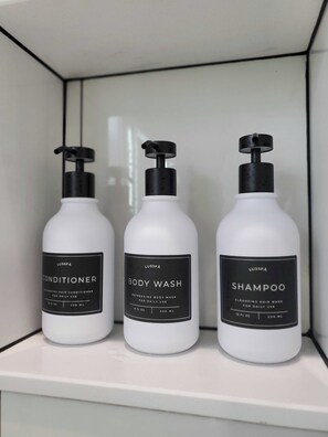 Drei Flaschen Körperpflegeprodukte von Lusspa auf einem weißen Regal.