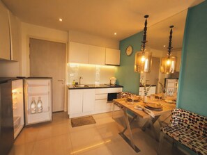 A modern kitchen with white cabinets, a dining table set for four, and pendant lights. - Atlantis resort condo Pattaya - One bedroom & living room all included apartment (Muang Pattaya)