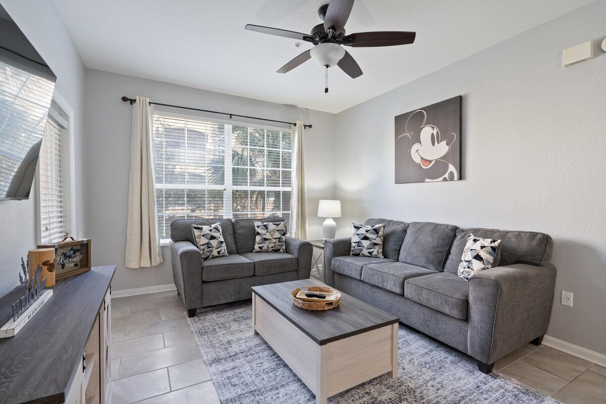 A modern living room with two grey sofas, a coffee table, and a ceiling fan.