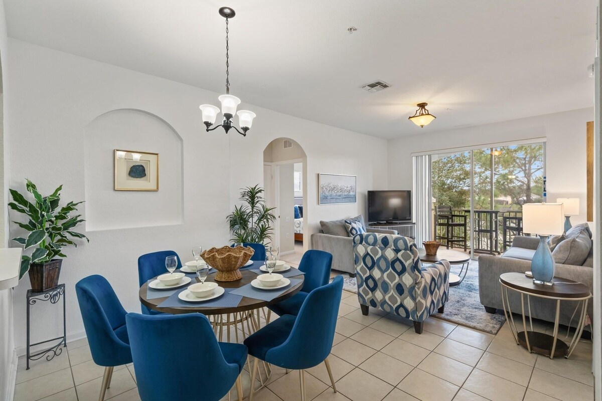 A modern living room with a dining area, a television, and a balcony with outdoor seating.