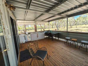 An outdoor kitchen area with a dining table and chairs, a refrigerator, and a sink.