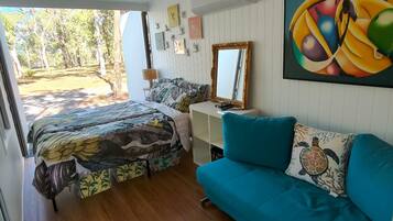 A room with a bed, a sofa, a mirror, and a painting on the wall.