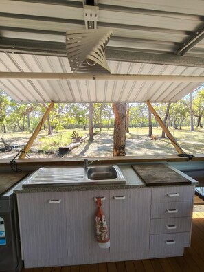 A kitchen with a sink, cabinets, and a view of a park.
