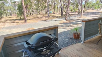 Ein überdachter Außenbereich mit Grill und Wasserspeicher auf einer Holzterrasse.