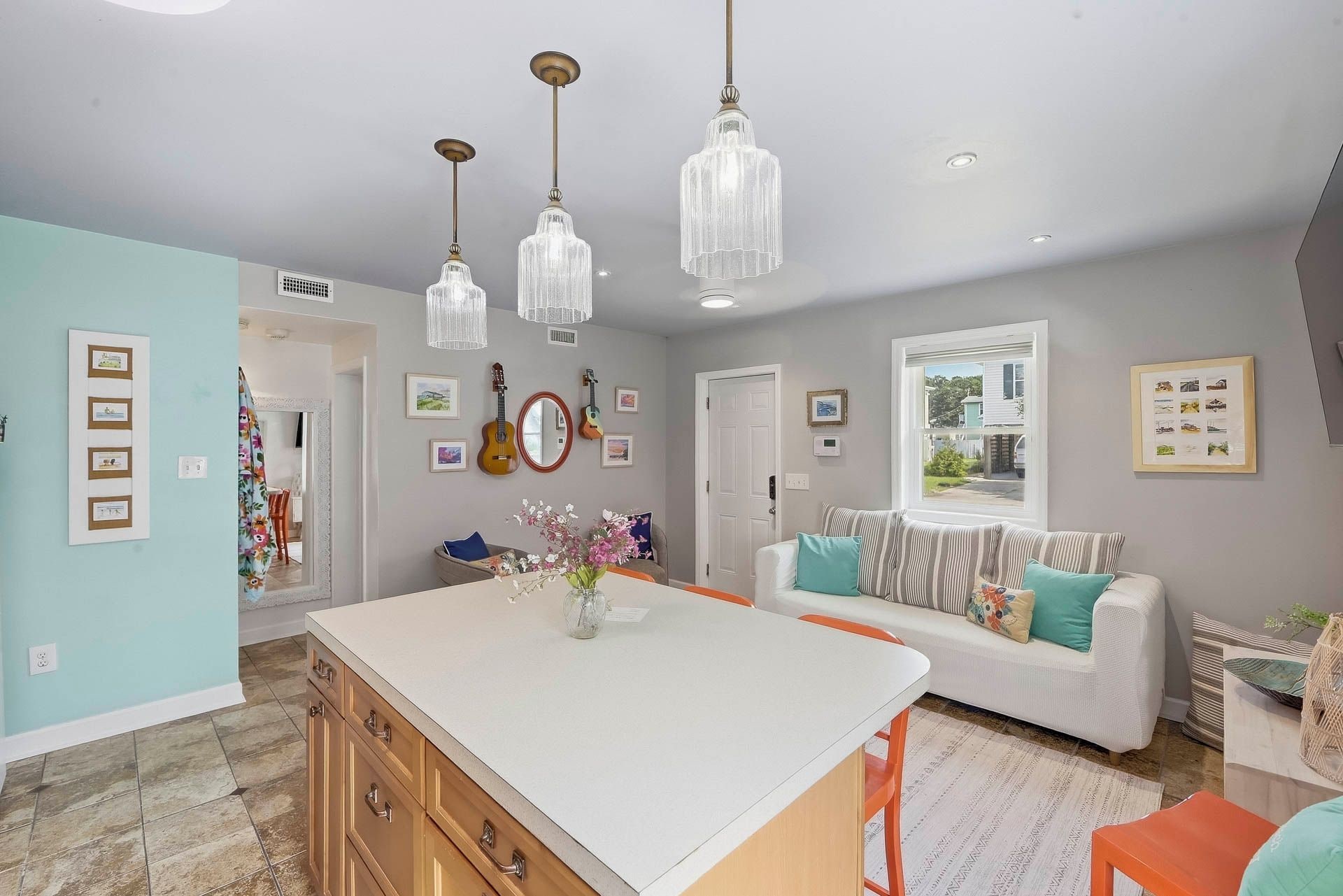 A kitchen with a central island, pendant lights, and wall-mounted guitars.