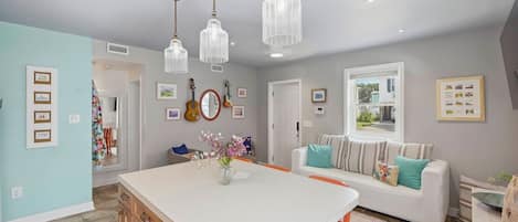 A kitchen with a central island, pendant lights, and wall-mounted guitars.