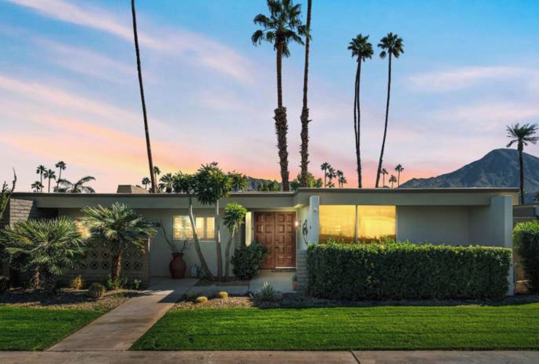 A modern two-story house with a front entrance, a driveway, and a well-maintained lawn.