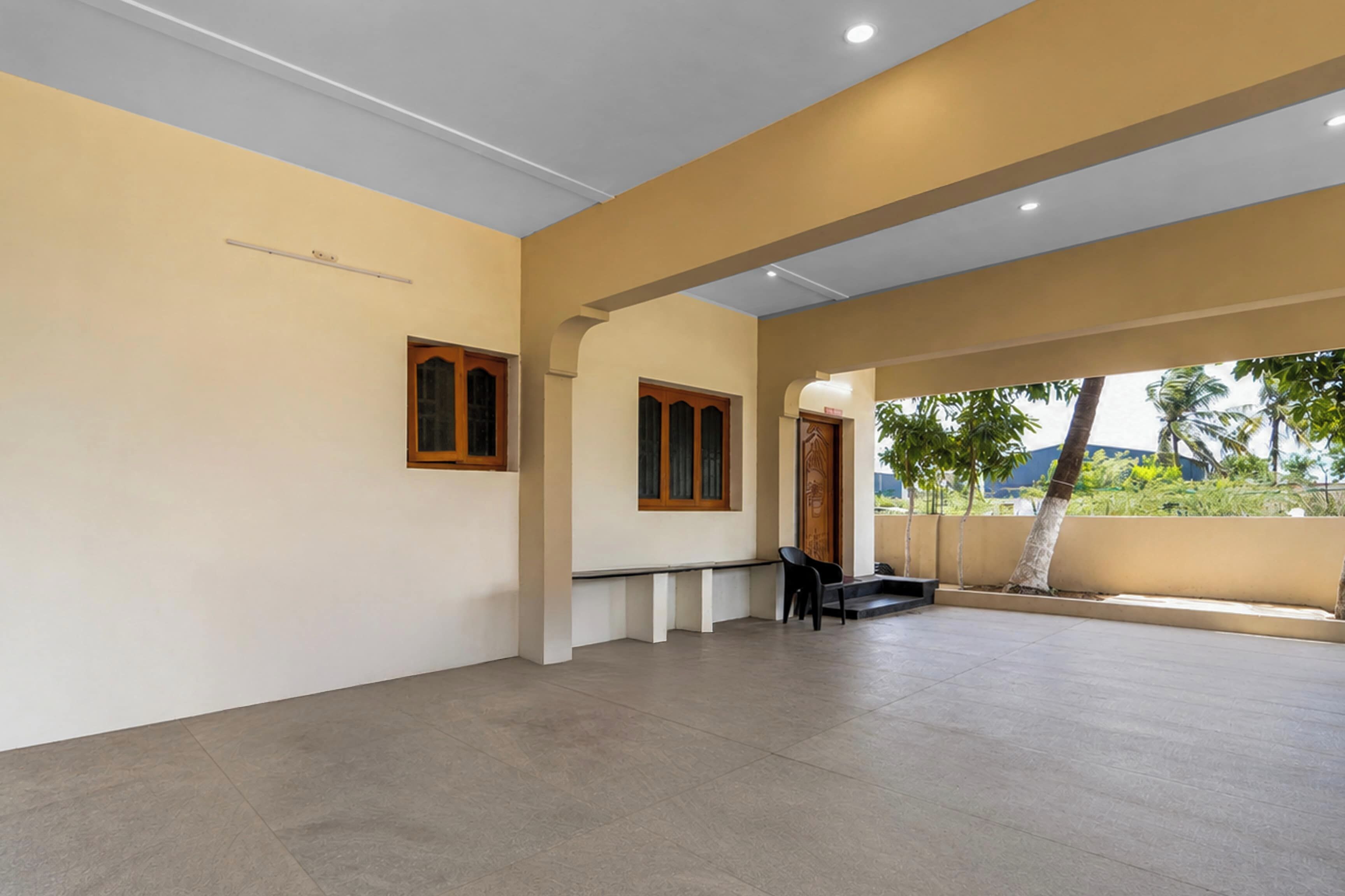 Un espacio interior amplio con techo alto, una banca y una puerta que da al exterior.