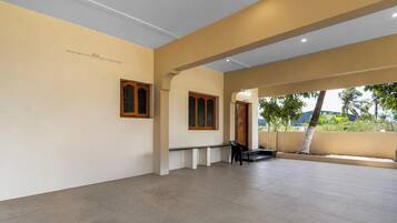 Un espacio interior amplio con techo alto, una banca y una puerta que da al exterior.