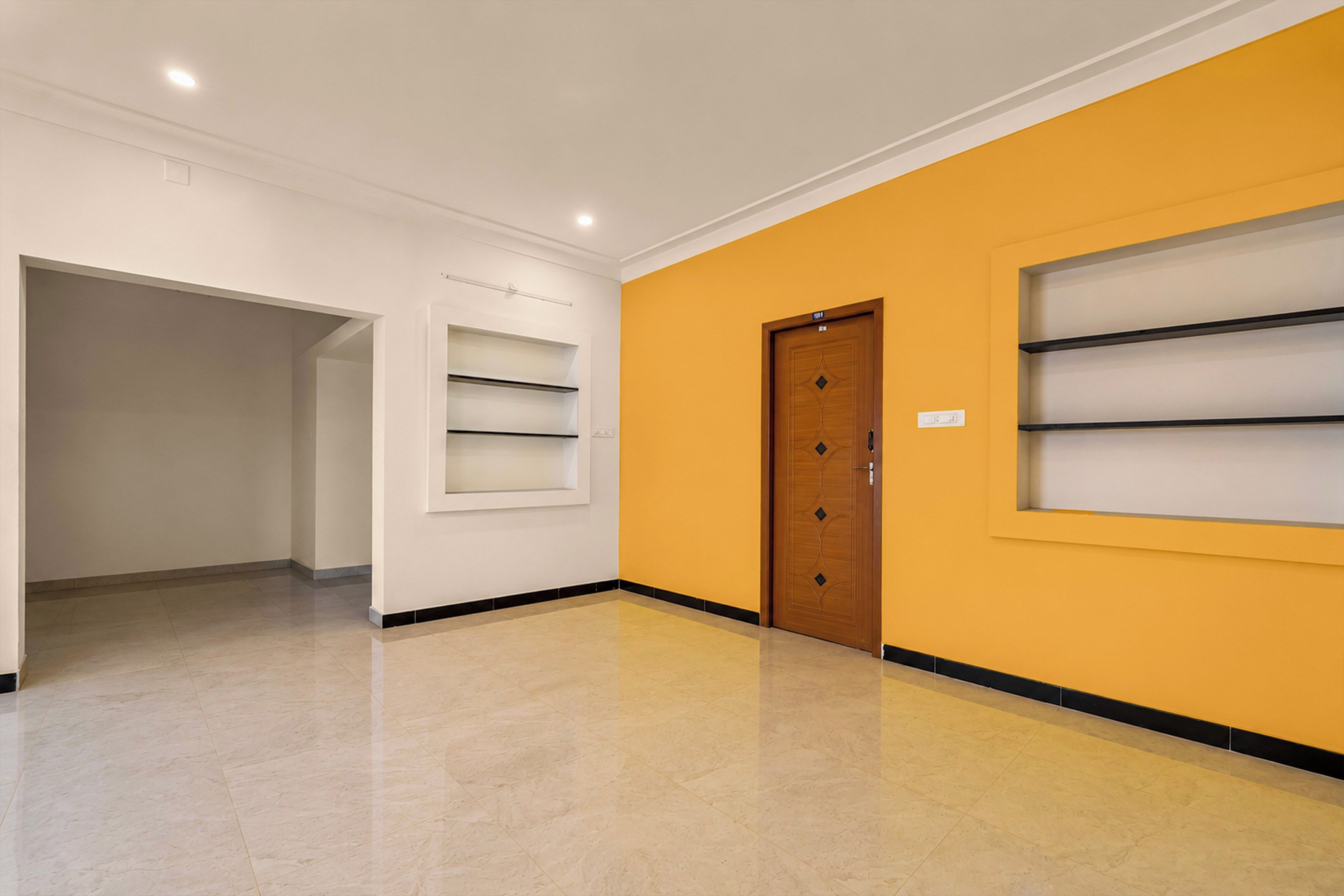 A hallway with a wooden door, white walls, and a yellow accent wall.