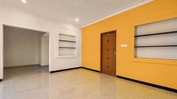 A hallway with a wooden door, white walls, and a yellow accent wall.