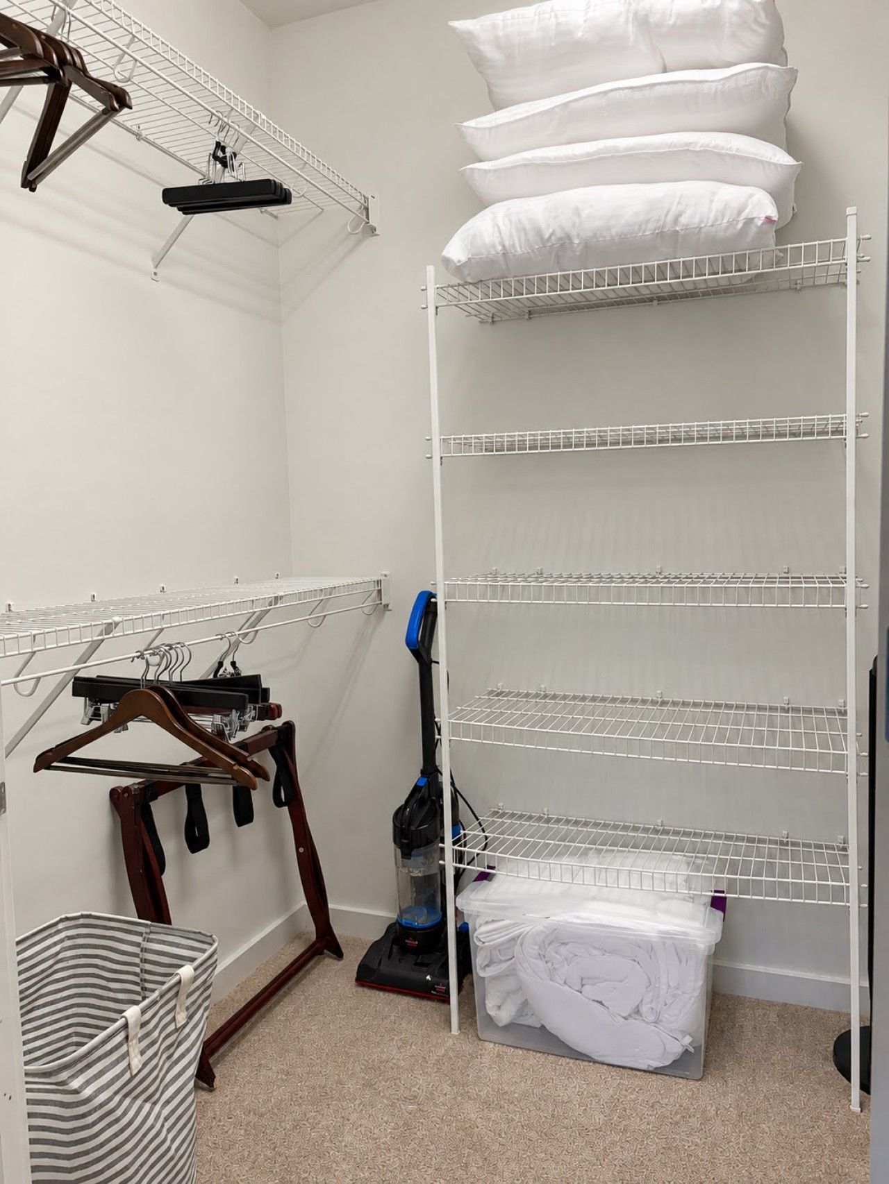 A laundry room with a drying rack, a vacuum cleaner, and a storage bin.