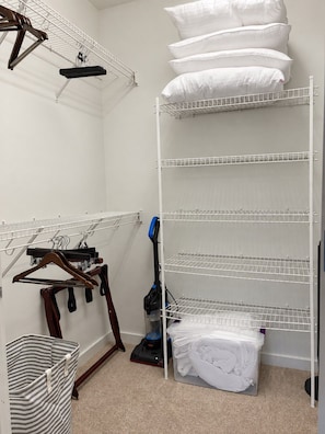 A laundry room with a drying rack, a vacuum cleaner, and a storage bin. - Third Ward 2BR + Den 2-Story Penthouse | Sleeps 10 (Milwaukee)