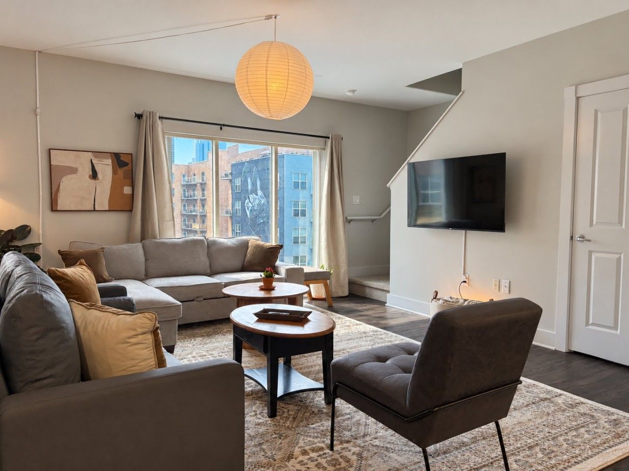 Un salon moderne comprenant un canapé, un fauteuil, une table basse et un téléviseur à écran plat.