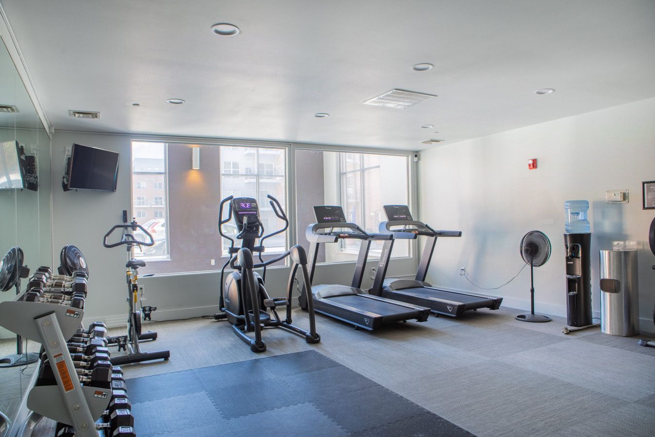A gym with treadmills, a stationary bike, and free weights.