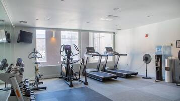 A gym with treadmills, a stationary bike, and free weights.