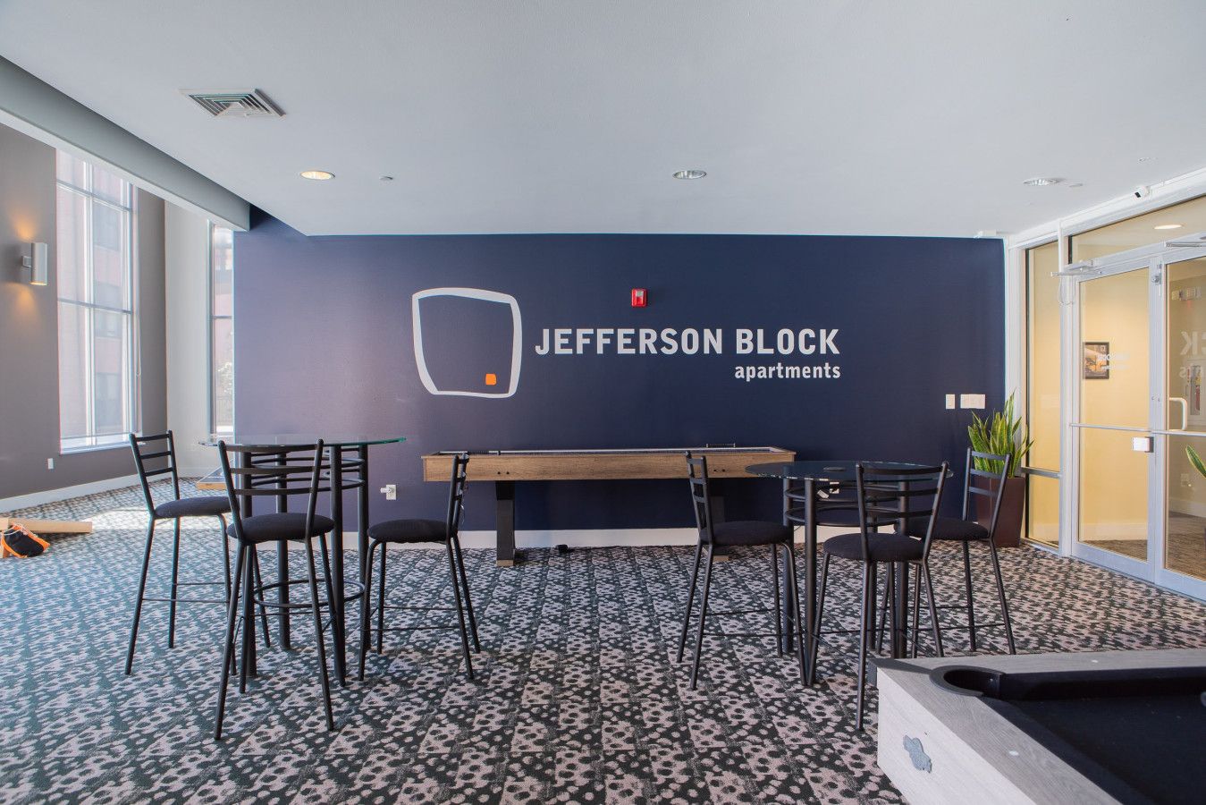 A conference room with a dark blue wall, a logo, and a table with chairs.