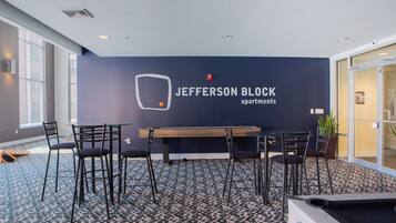 A conference room with a dark blue wall, a logo, and a table with chairs.