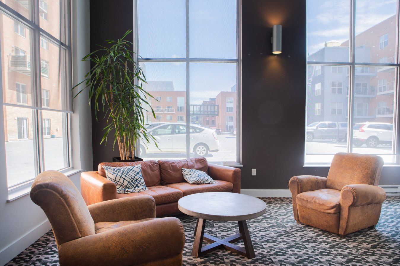 Ein stilvoller Lounge-Bereich mit Ledersofas, einem runden Tisch und einer großen Pflanze in einem Topf.