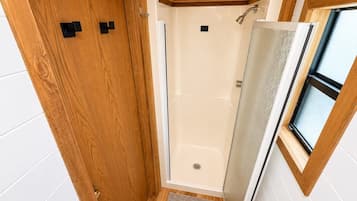 Ein kleines, abgeschlossenes Badezimmer mit Dusche, einer Tür und einem Fenster.