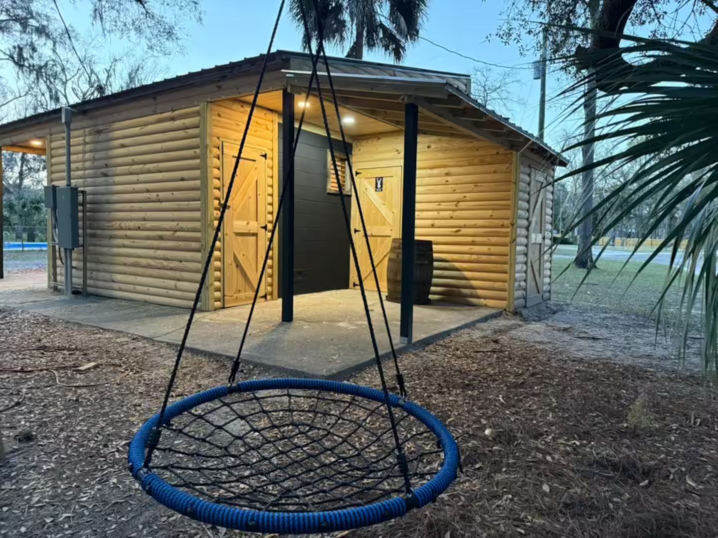 A log cabin with a swing hanging in front.