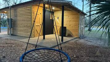 A log cabin with a swing hanging in front.