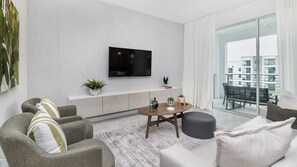 A modern living room with a flat-screen TV, grey sofas, a coffee table, and a balcony with a view of buildings. - Pxc3180-303 2 Bedroom Condo (Kissimmee)