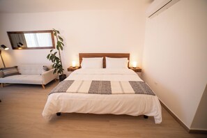 A neatly made bed with a wooden headboard, two bedside lamps, and a bedside table. - Vrbo Property (Cabo San Lucas)