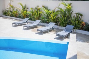 A pool area with lounge chairs and tropical plants. - Vrbo Property (Cabo San Lucas)