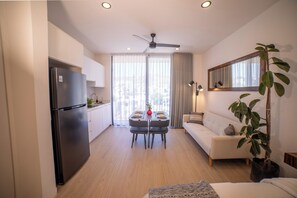 A modern kitchen with a built-in refrigerator, a dining area with a table and chairs, a sofa, and a large window with curtains. - Vrbo Property (Cabo San Lucas)