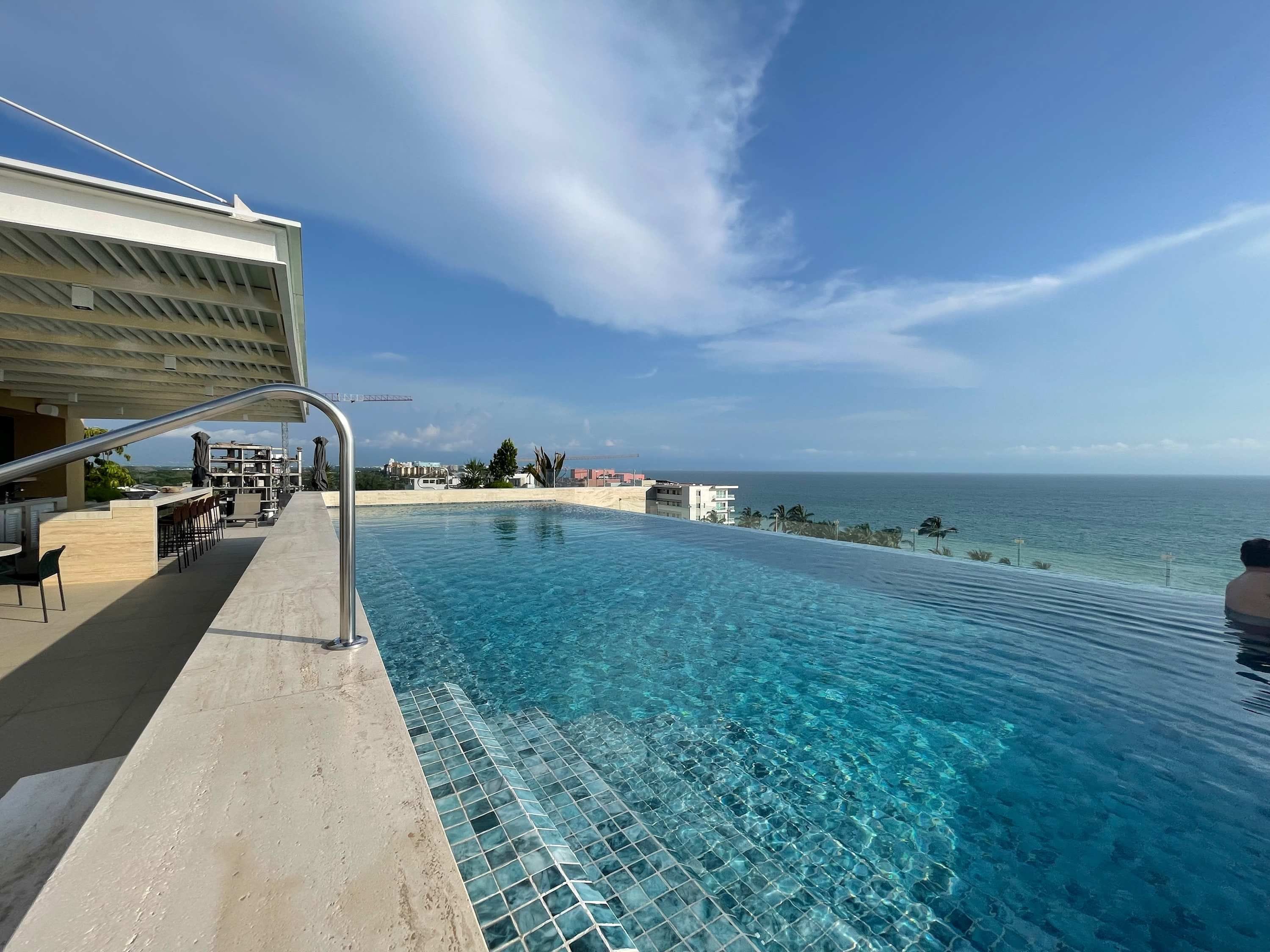 Ein Infinity-Pool mit freiem Blick auf den Ozean, eine Bar und ein überdachter Sitzbereich.