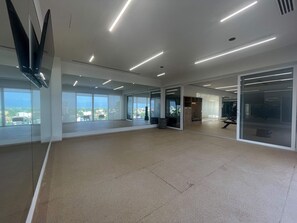 A spacious office with large windows, a glass partition, and a view of the cityscape. - 2BR w/ Rooftop Infinity Pool & Padel Court (Bucerías)