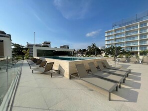 A rooftop pool area with sun loungers, a swimming pool, and a view of surrounding buildings. - 2BR w/ Rooftop Infinity Pool & Padel Court (Bucerías)