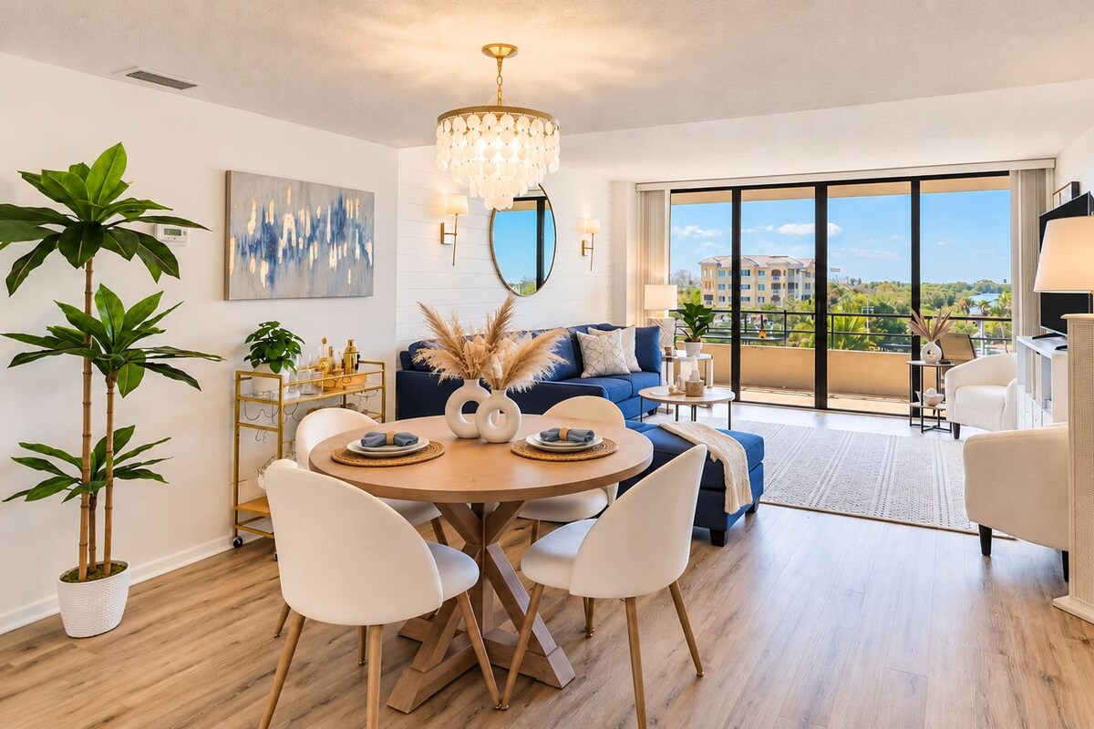 Ein modernes Wohnzimmer mit Essbereich, großen Fenstern und Blick auf die Stadt.