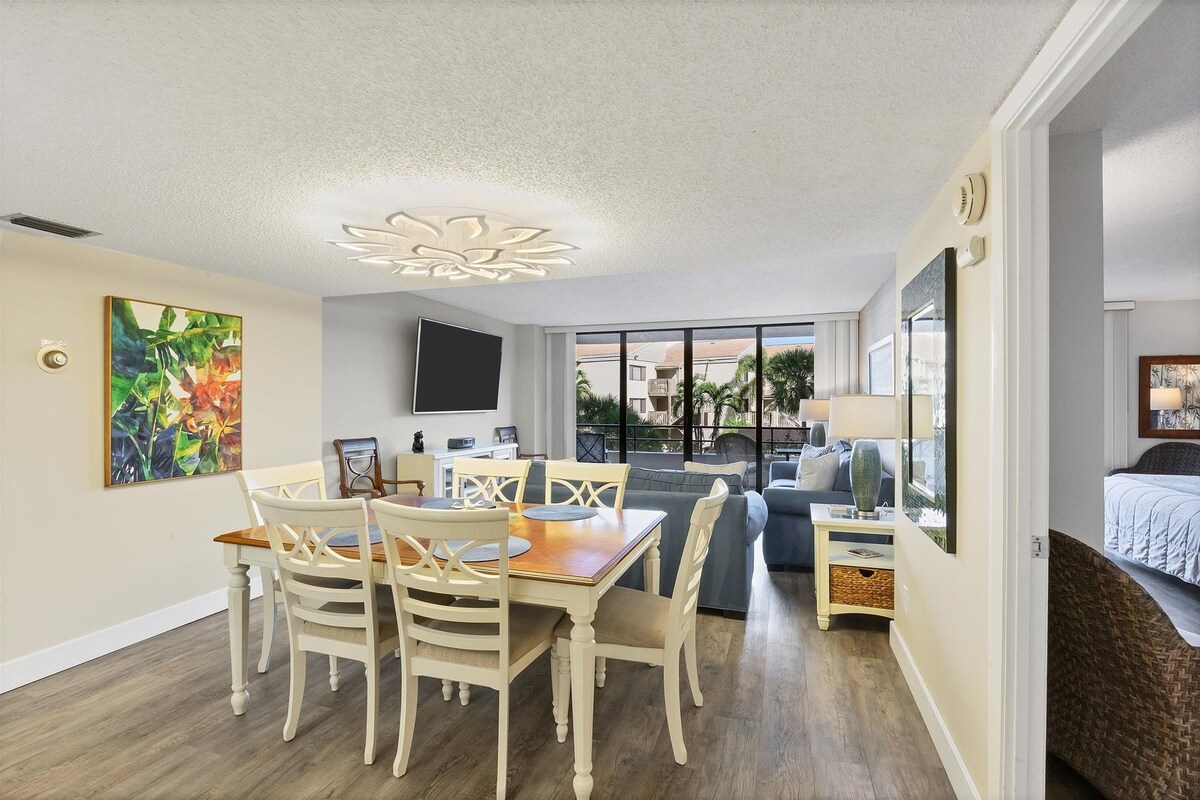 Ein geräumiges Wohnzimmer mit Esstisch und Stühlen, einer Couch und einem an der Wand befestigten Fernseher.