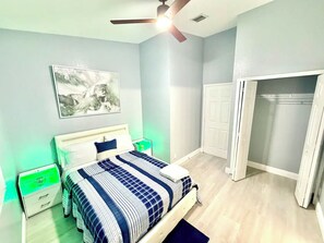 A bedroom with a bed, a ceiling fan, a nightstand, a bedside table, a wall-mounted artwork, and a closet. - Entire property 3 Bedroom/2.5 Bath in Boynton Beach (Boynton Beach)