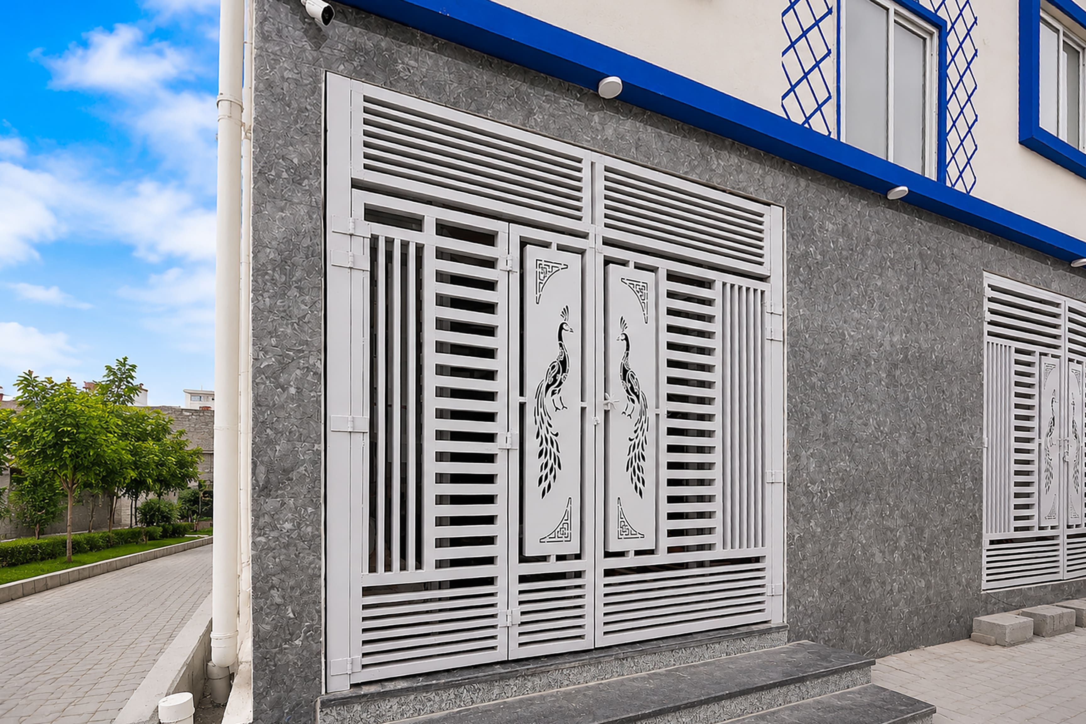 Facciata di un edificio con persiane metalliche decorative e rifiniture blu.