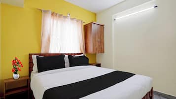Un dormitorio con cama, cabecera de madera, mesitas de noche, armario, ventana con cortinas e iluminación empotrada en la pared.